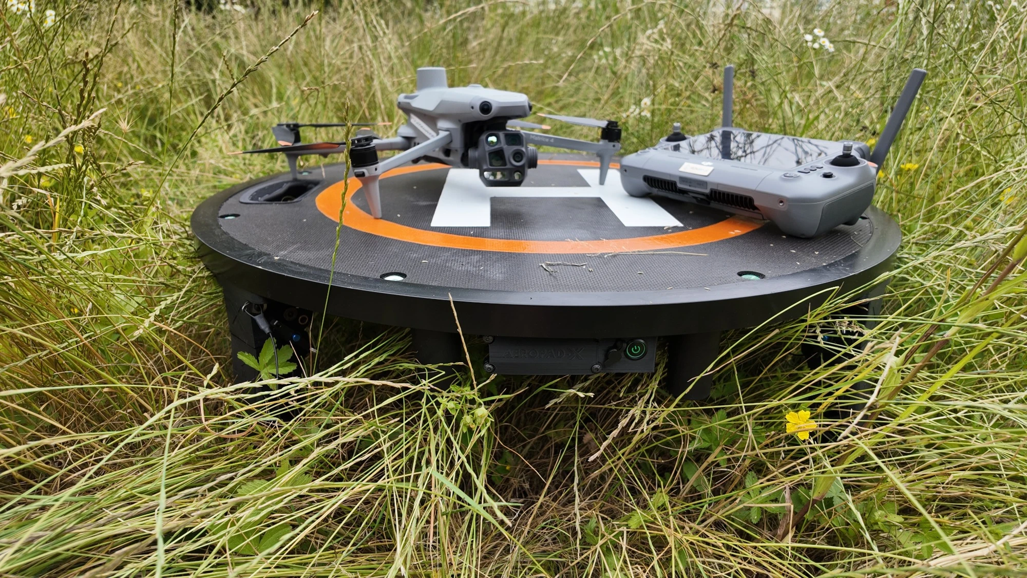 AEROPAD-X elevated landing platform supporting a drone and controller in tall grass